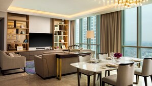 A modern living room with a large TV, comfortable seating, a dining area, and a city view. - Intercontinental Residence Jakarta Pondok Indah (Jakarta)
