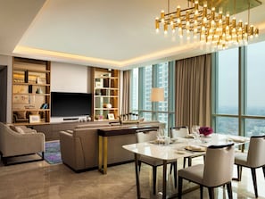 A modern living room with a large TV, comfortable seating, a dining area, and a city view. - Intercontinental Residence Jakarta Pondok Indah (Jakarta)
