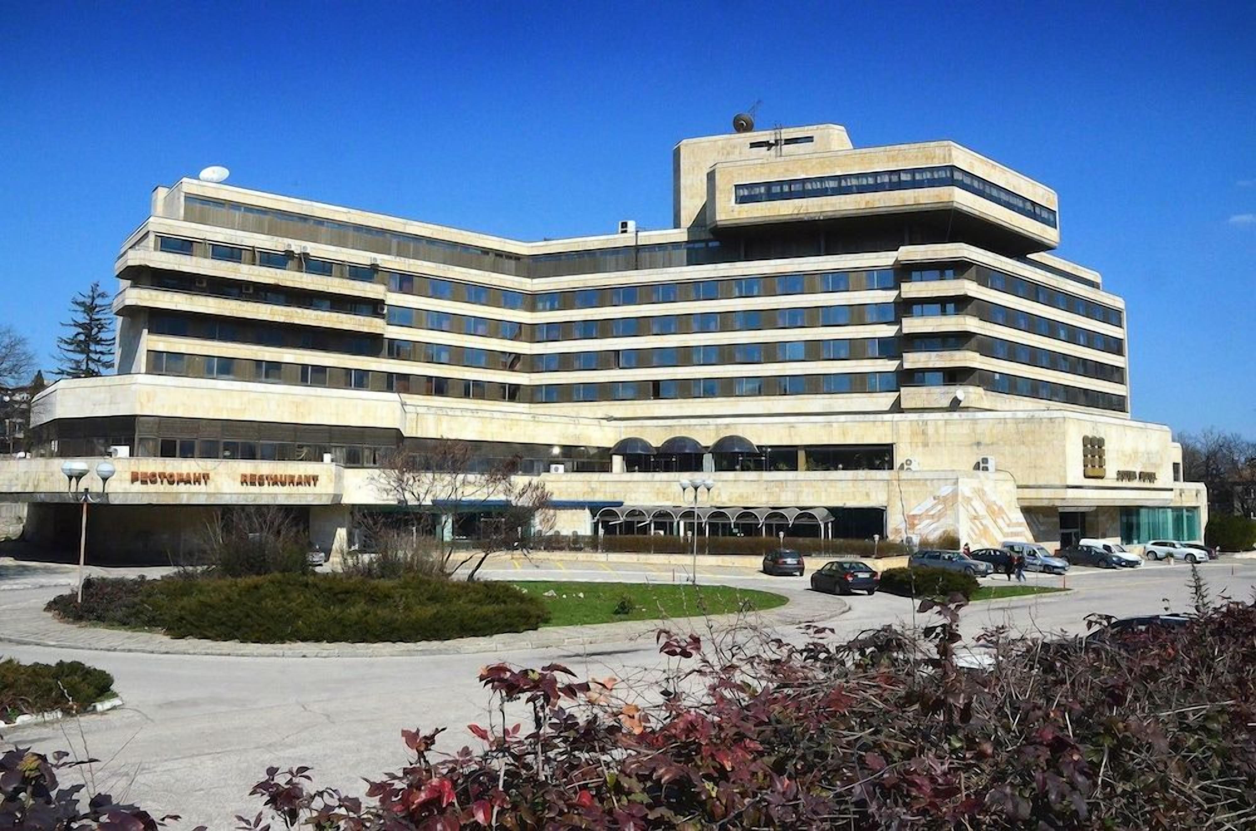 Un edificio a più piani con tetto piatto, ampie finestre e un'insegna che indica un ristorante.