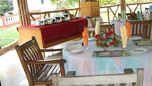 Ein Essbereich im Freien mit Holztischen und -stühlen, einem Buffet und Blick auf den Garten.
