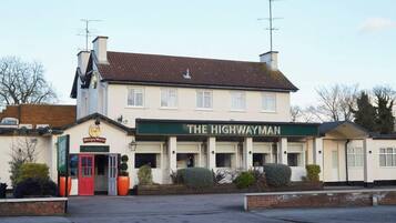 Un edificio de dos pisos con un letrero que dice 'THE HIGHWAYMAN' y una puerta roja.