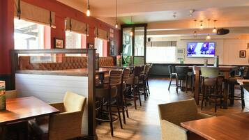 Un restaurante con cabinas y mesas, una pantalla de televisión y una zona de bar.