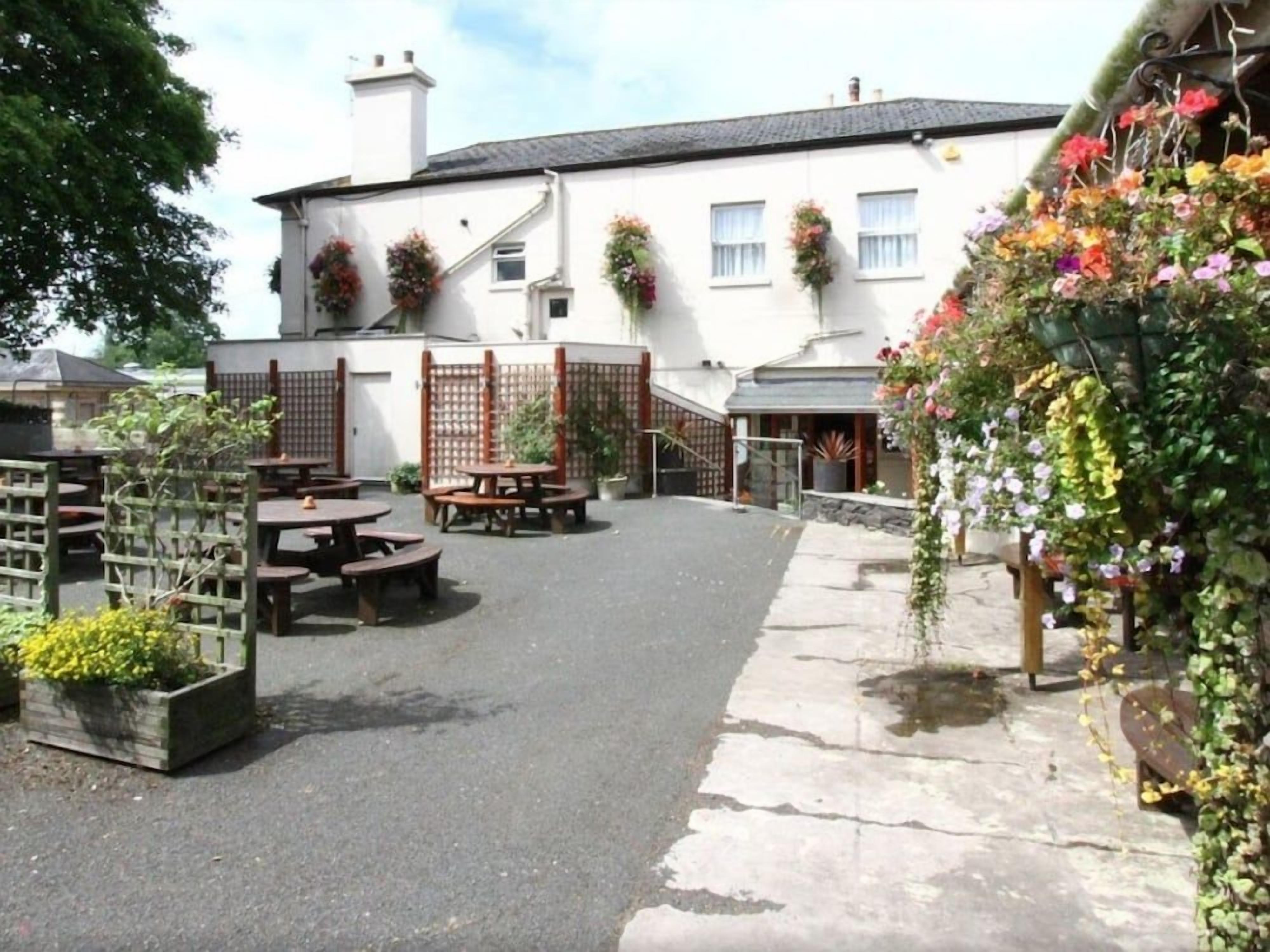 A courtyard with outdoor seating, a building with flower boxes, and a garden area.