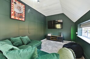 Habitació amb tons verds, un sofà, una butaca i un quadre.