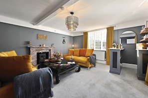 A living room with a fireplace, a sofa, a coffee table, and a chandelier. - Blackham Farm  -  a holiday let sleeping 14 guests  in 6 bedrooms (Tunbridge Wells)
