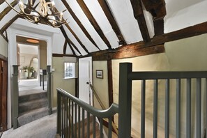A staircase with a wooden handrail and a white ceiling with exposed beams.