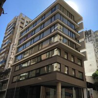 Un edificio de varios pisos con un diseño arquitectónico moderno, que presenta una serie de balcones y grandes ventanales.