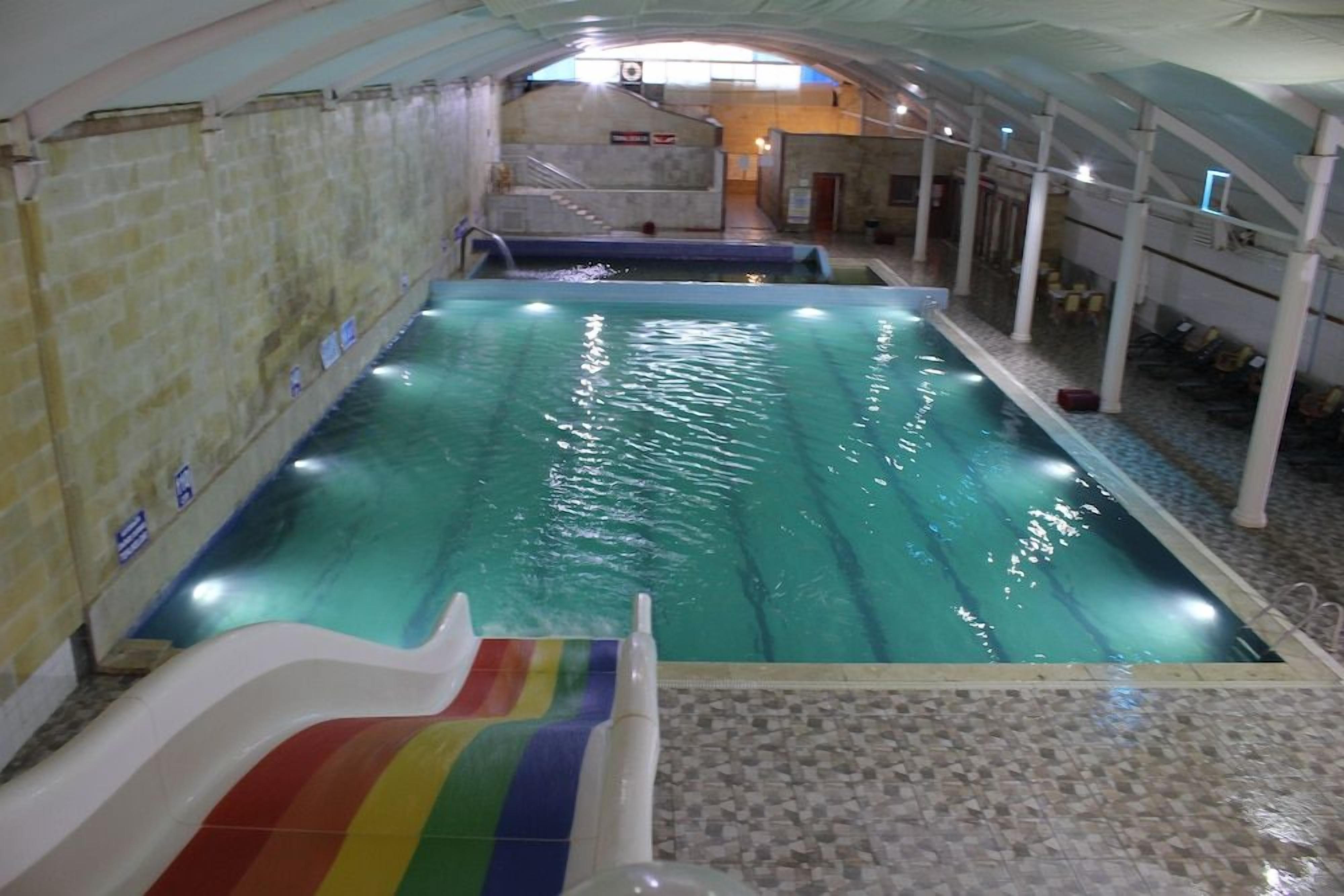 Ein hallenbad mit Rutsche, gefliesten Wänden und gefliestem Boden.