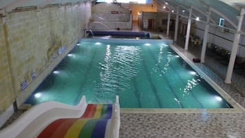 Ein hallenbad mit Rutsche, gefliesten Wänden und gefliestem Boden.
