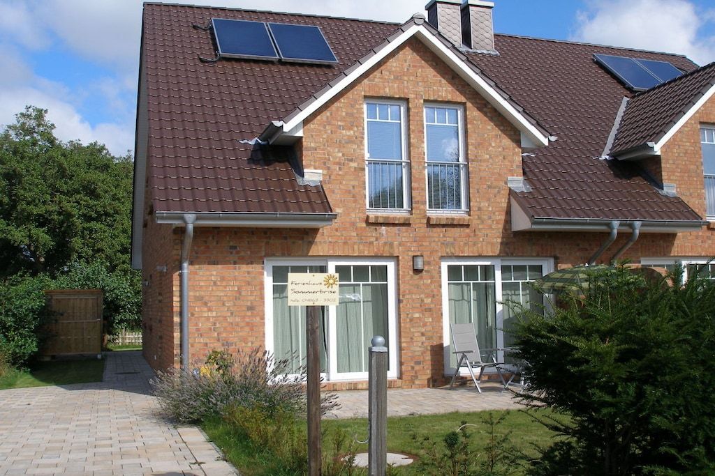 A two-story building with a brick facade, solar panels on the roof, and a sign indicating a summerhouse.