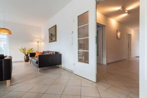 A spacious living area with a sofa, a lamp, and a vase of flowers. - Holiday home with 3 bedrooms (St.Peter-Ording)