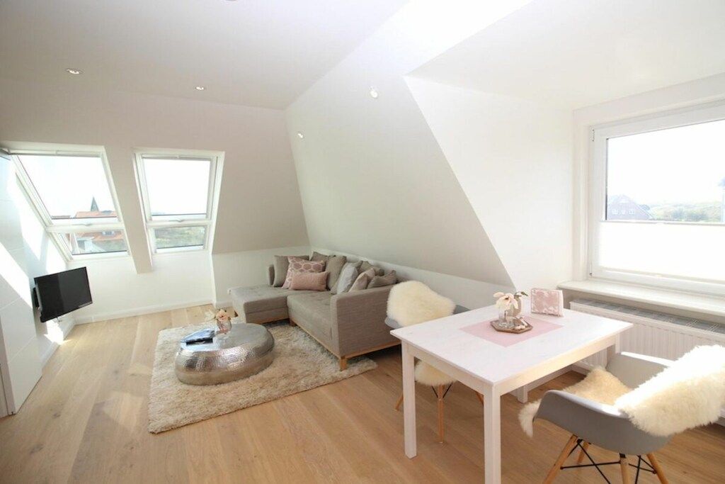 A modern living room with a sofa, a dining table, and a TV.