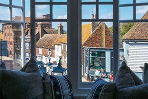 A view from a window with a view of a town street, including buildings and a shop with a sign.