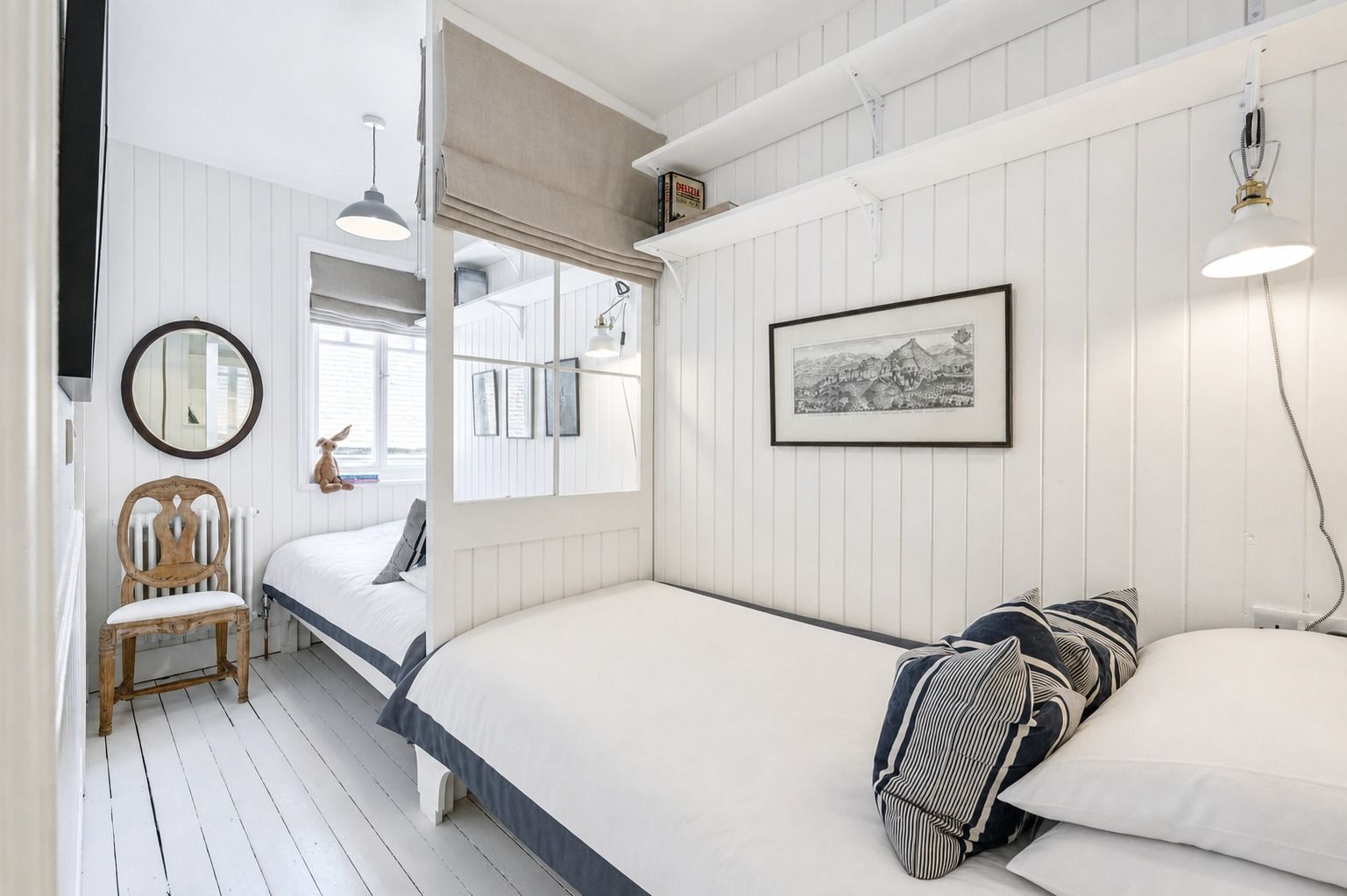 A bedroom with a bed, a chair, a bedside table, a mirror, and a framed picture on the wall.