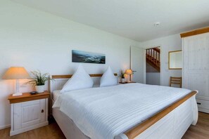 Ein Schlafzimmer mit einem Bett, Nachttischen, einem Gemälde und einer Treppe.