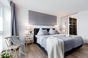 A modern bedroom with a bed, bedside tables, a mirror, and a wardrobe. - Holiday apartment with 1 bedroom (Ostseeresort Olpenitz)