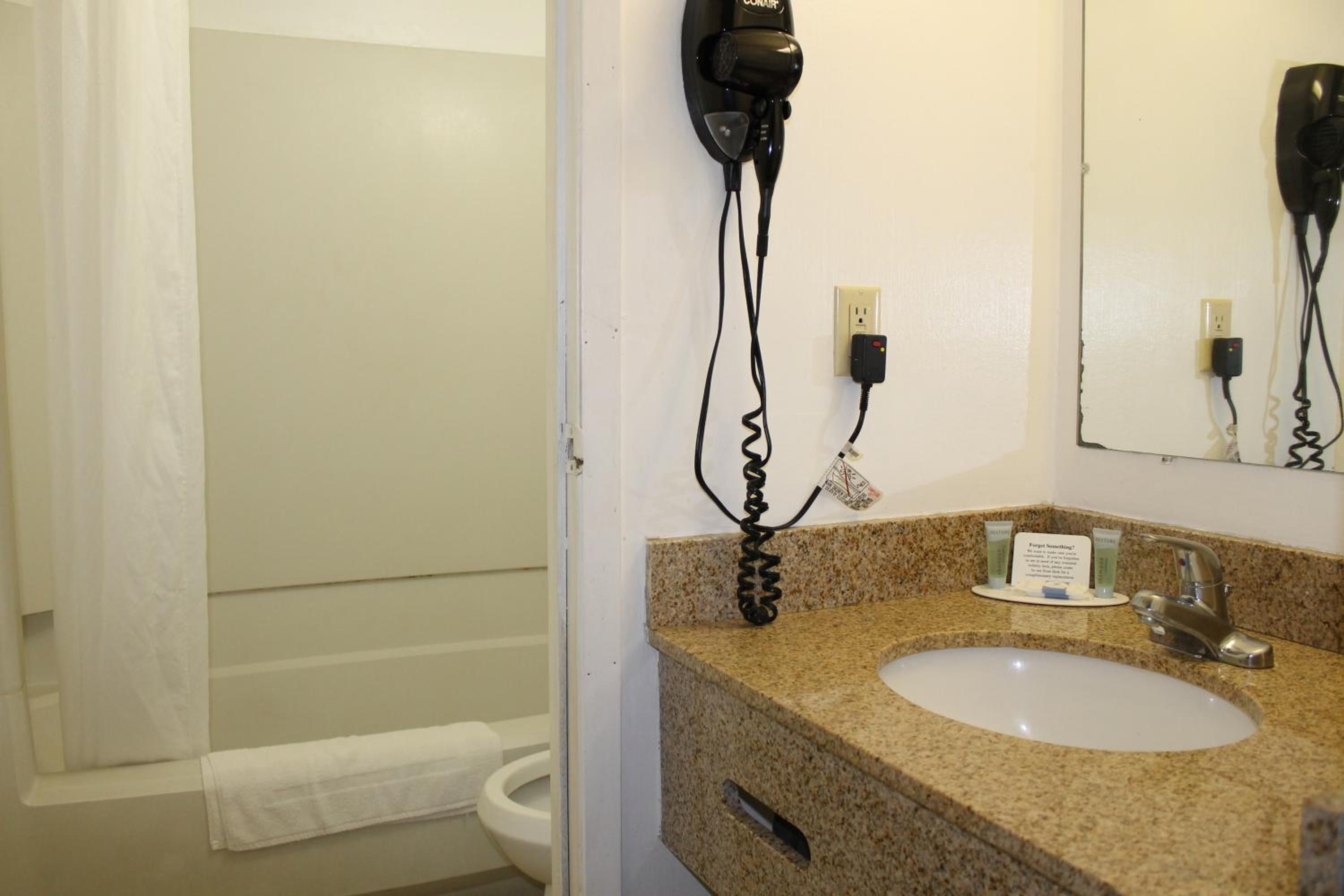 A bathroom with a sink, mirror, and hair dryer mounted on the wall.