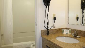 A bathroom with a sink, mirror, and hair dryer mounted on the wall.