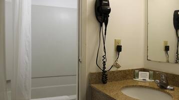 A bathroom with a hairdryer mounted on the wall, a sink with a faucet, and a mirror above the sink.