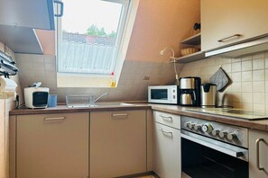 Eine kompakte Küche mit Mikrowelle, Kaffeemaschine und Backofen.