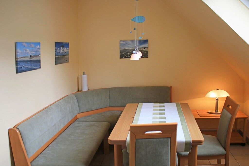 A cozy dining area with a table and chairs, a lamp, and three framed pictures on the wall.