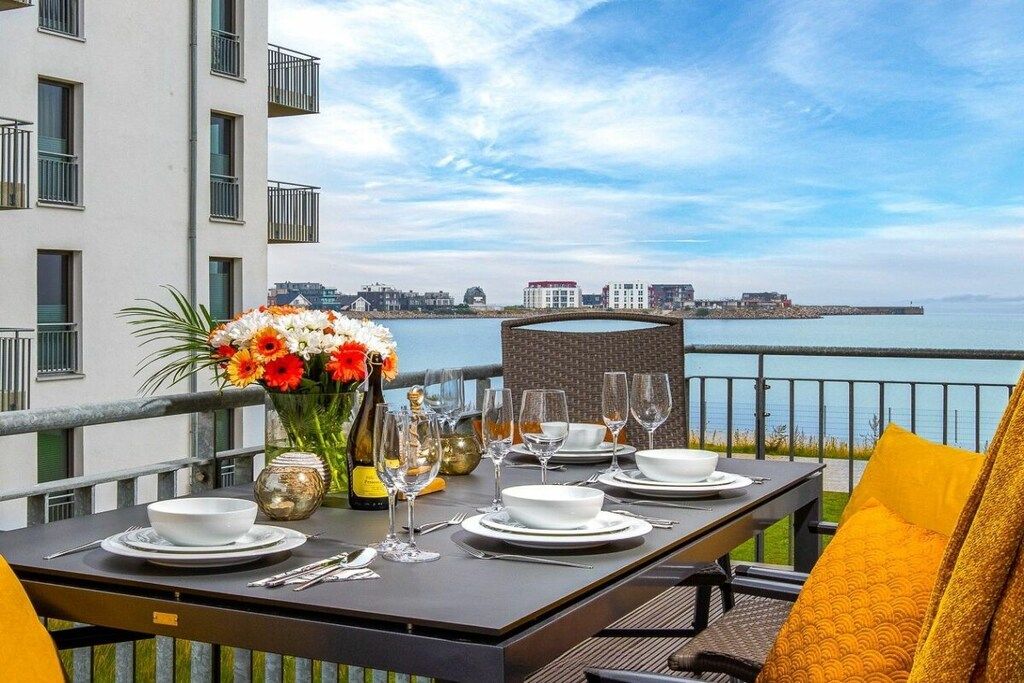 Een gedekte tafel met uitzicht op de zee en gebouwen op de achtergrond.