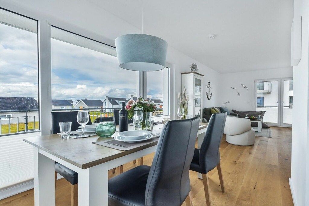 A modern dining area with a table set for two, large windows offering a view of the city, and a contemporary pendant light.