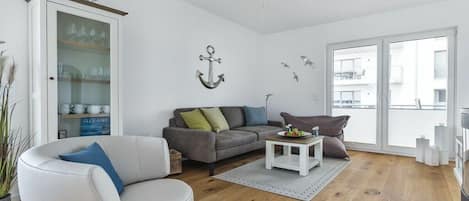 Un salon moderne avec un canapé gris, un fauteuil blanc et une vitrine.