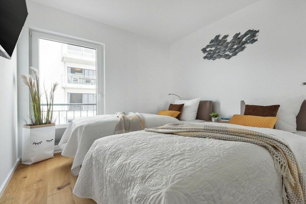 Camera da letto moderna con un letto grande, due comodini, un'opera d'arte appesa al muro e una finestra vista su un edificio.