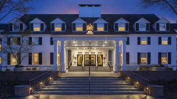 A large, multi-story building with a grand entrance, featuring a central staircase and a symmetrical facade.