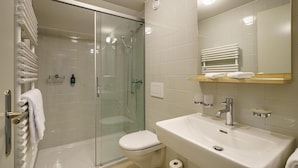 Uma casa de banho moderna com chuveiro de cabine de vidro, lavatório branco e sanita.