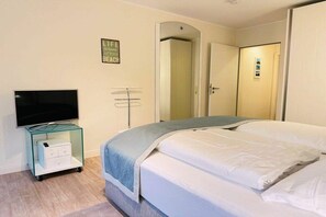 A bedroom with a bed, a television on a glass cabinet, a door with a mirror, and a sign on the wall. - Sea lavender in the Frisian residence (St. Peter Ording)
