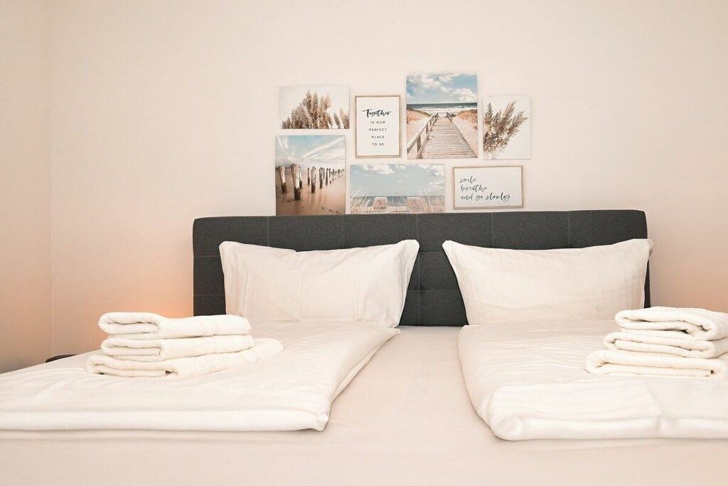 A double bed with white linens and pillows, a dark headboard, and framed pictures on the wall.