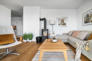 A modern living room with a sofa, a wooden coffee table, and a fireplace. - Apartment in Olpenitz with swimming pool (Olpenitz)