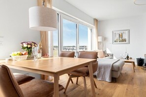 Una sala de estar moderna con comedor, ventanas amplias y vista a la ciudad.
