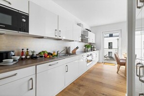 Eine moderne Küche mit weißen Schränken, einer Bosch-Mikrowelle und einer Holzausziehtafel.