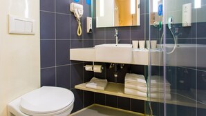 Un baño moderno con inodoro, lavamanos y ducha con mampara de vidrio.