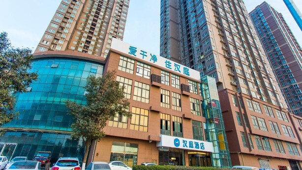 Un hotel con fachada de vidrio moderna y varios edificios altos al fondo.