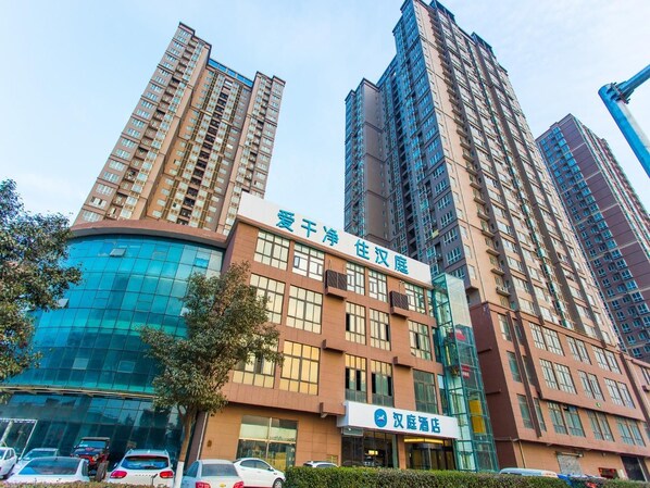 Um hotel com fachada de vidro moderna e vários edifícios altos ao fundo.