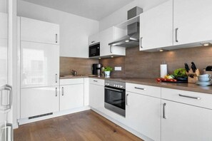 A modern kitchen with white cabinets, a stainless steel oven, and a microwave. - Apartment in Olpenitz with swimming pool (Olpenitz)