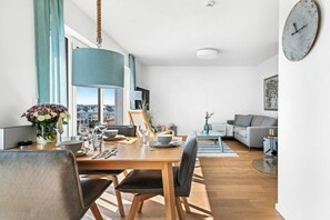 A modern living space with a dining area, a sofa, and a large window offering a city view. - Apartment in Olpenitz with swimming pool (Olpenitz)
