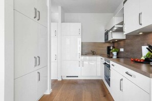 A modern kitchen with white cabinetry, a wooden countertop, and a built-in oven. - Apartment in Olpenitz with swimming pool (Olpenitz)