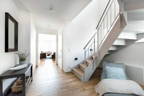 Ein modernes Interieur mit einer Treppe, einem Konsolentisch mit Körben und Blick in den Wohnbereich.