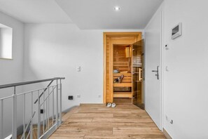 A hallway with a wooden floor, a metal railing, and a wooden door leading to a room with a built-in wardrobe. - Holiday apartment with 1 bedroom (Ostseeresort Olpenitz)