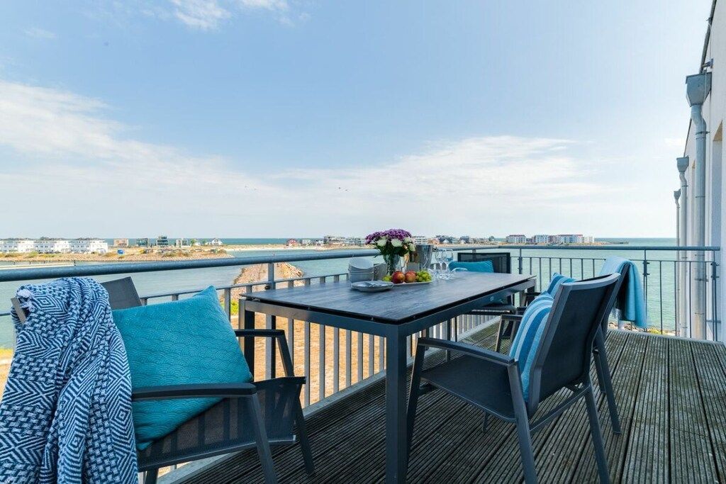 Een terras met tafel en stoelen met uitzicht op een wateroppervlak.