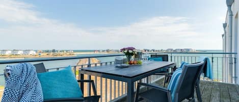 A deck with a table and chairs overlooking a body of water.
