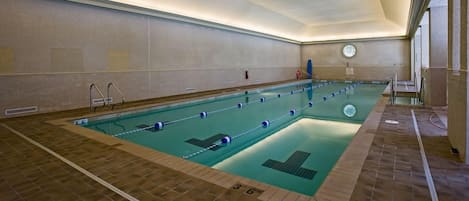 An indoor swimming pool with lane markers, a tiled floor, and a ceiling with recessed lighting.