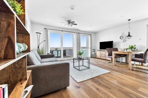 A modern living room with a sofa, coffee table, and dining area with chairs and a table. - Holiday apartment with 1 bedroom (Kappeln)