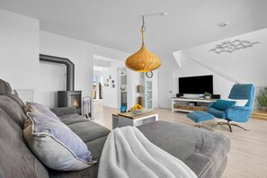 Ein modernes Wohnzimmer mit einer Couch, einem Fernseher und einem Kamin.