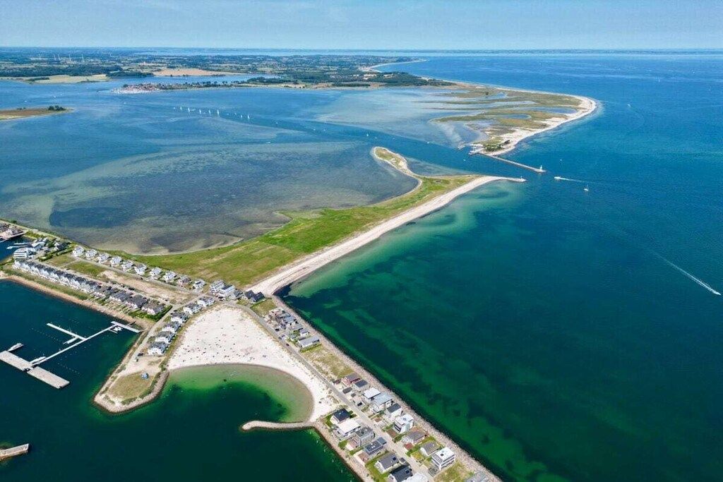 An aerial view of a coastal area with a marina, a beach, and residential buildings.